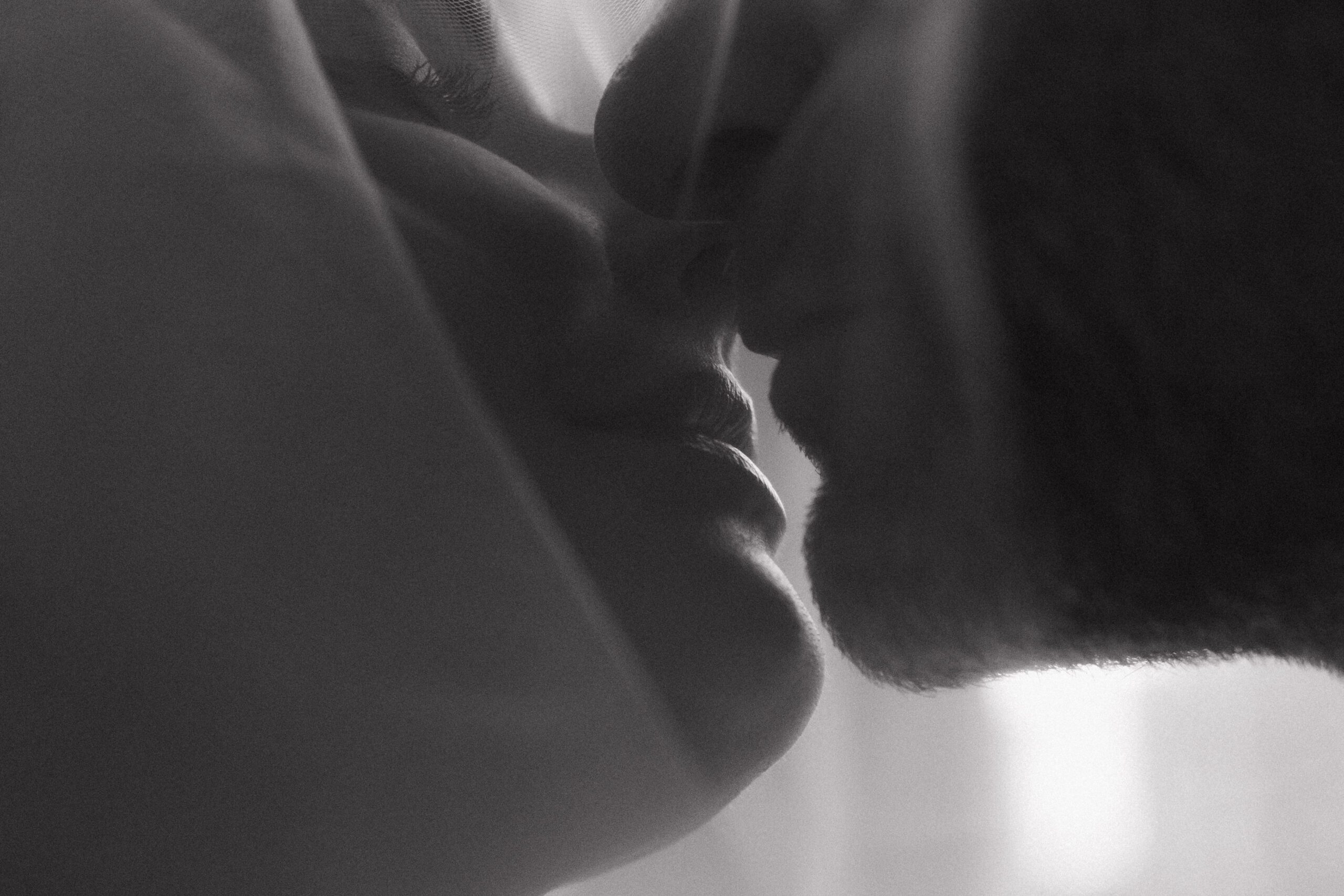 black and white close up of couple kissing under a veil